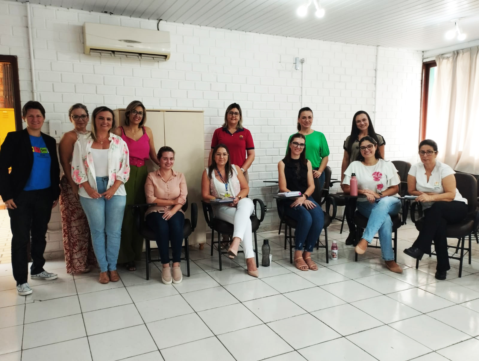 Ambiente interno, sala de aula, 12 pessoas posam para foto