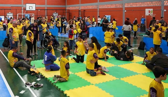 Imagem de crianças com camisetas amarelas em ginásio, tatames verde e amarelo, texto - Inscrições abertas para o Festival Paralímpico 2024: evento gratuito ocorre dia 21/09 em São José