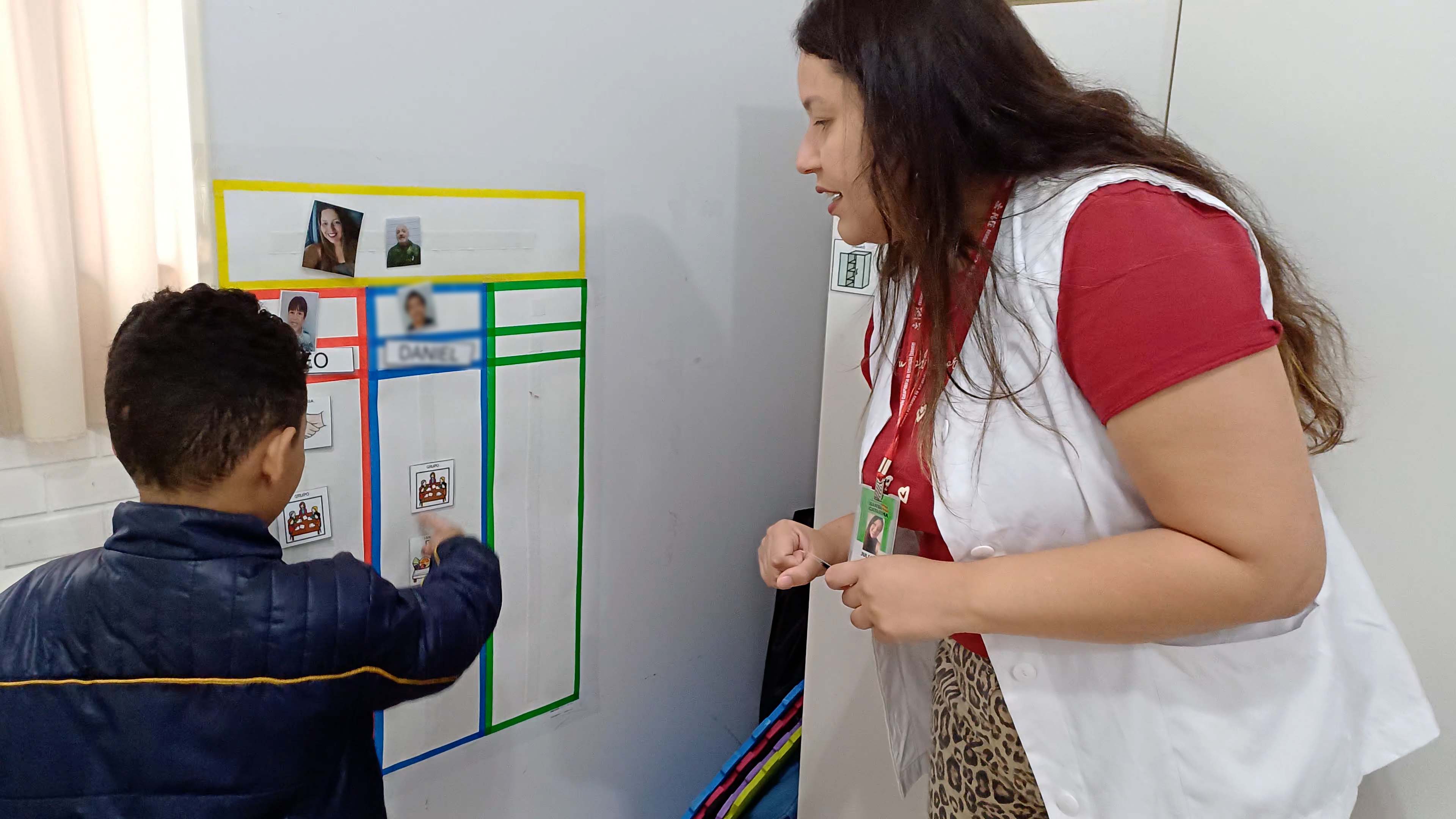 Professora ao lado de aluno mexem em quadro branco