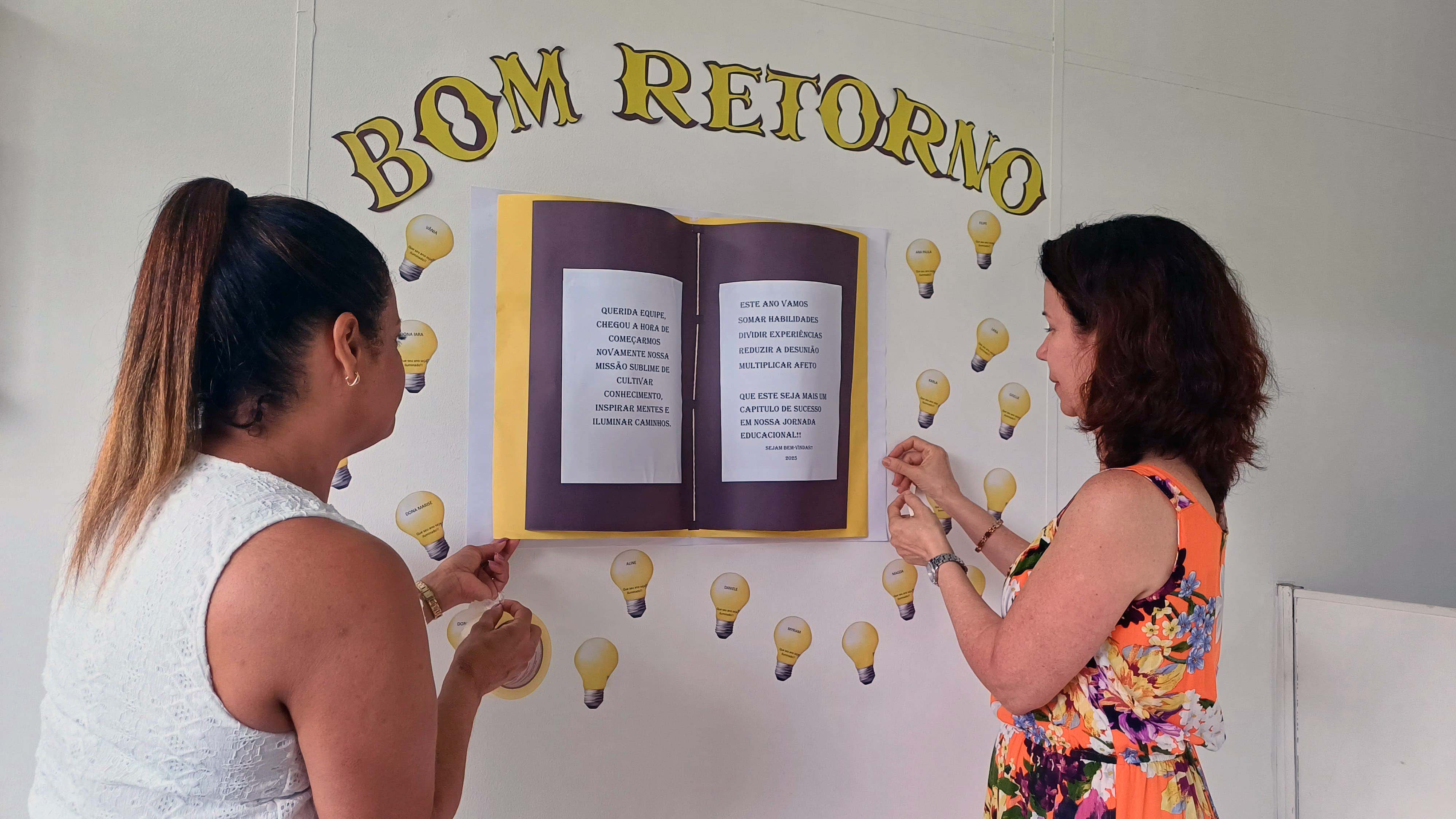 parede com frase escrita bom retorno, duas mulheres escrevem em cartaz na parede